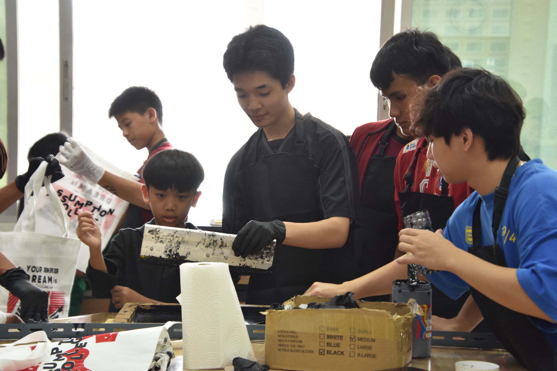 A student lifts an inked squeegee from the screen